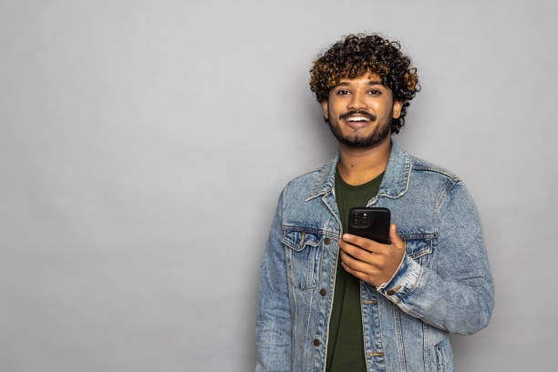 istock Excited indian business man using cell mobile phone isolated on gray background. 1475526980