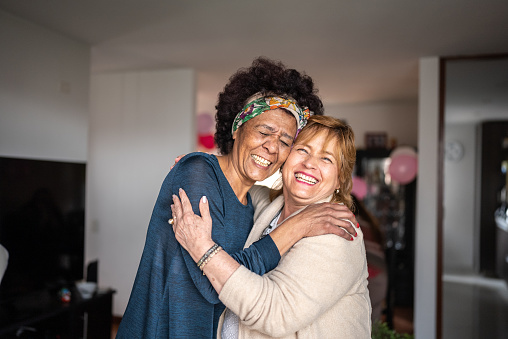 Portrait of senior friends embracing at home