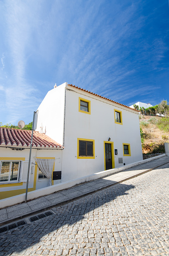 Typical whitewashed portuguese house in the street with steep slope. Salema village, Discrict Faro, Algarve, Southern Portugal.