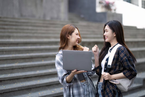 istock Cheerful Asian college two female students are talking, sharing ideas, working on their school project together 1475538698