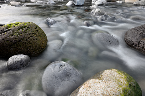 Mountain river with stones. Grey stones on strong flow of mountain river