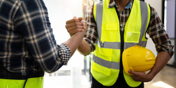 ingeniero de construcción y arquitecto con plano dándose la mano mientras está de pie en el sitio de construcción. concepto de construcción de viviendas - construction construction site handshake built structure fotografías e imágenes de stock