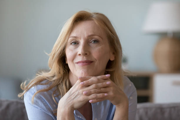 Attractive middle-aged woman resting on sofa look at camera stock photo