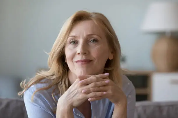 Photo of Attractive middle-aged woman resting on sofa look at camera