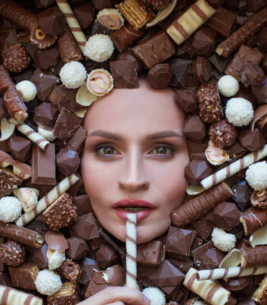 istock Healthy woman eating candy on chocolate background 1475546378