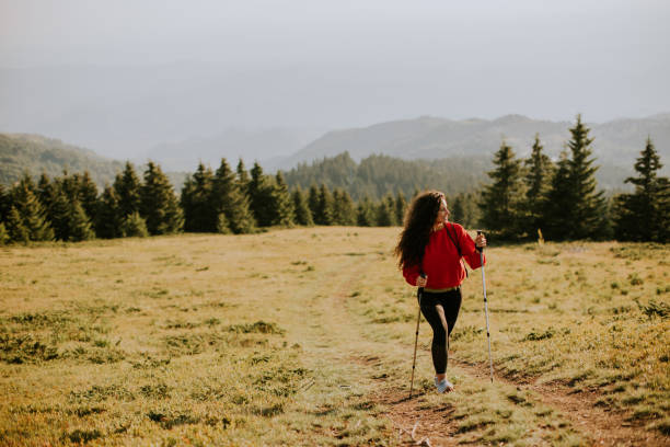istock Young woman walking with backpack over green hills 1475549546
