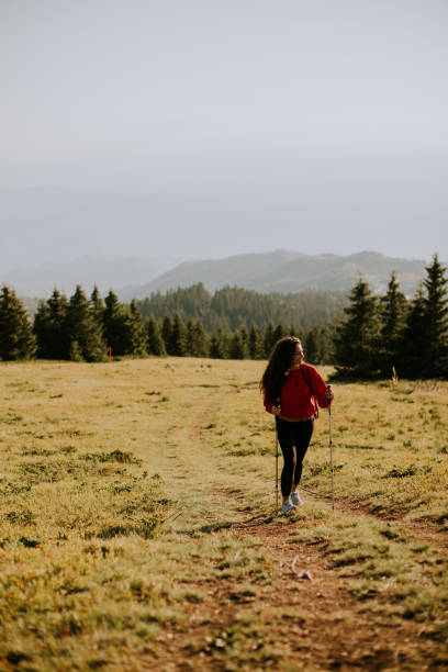 istock Young woman walking with backpack over green hills 1475549559
