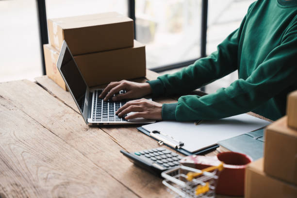 istock Small business owner using a laptop computer while working on online marketing packaging box and delivery, SME concept. 1475550581