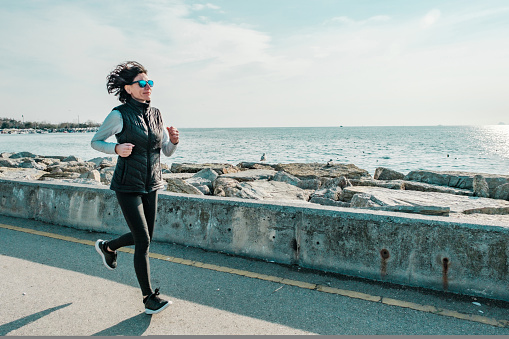 Healthy lifestyle concept: Sporty young fitness woman running training for marathon on sunny coast trail against city background on sunny day with sky and sea background. Female person in jogging outfit enjoying her morning run on sidewalk, staying active. Set of 16 images