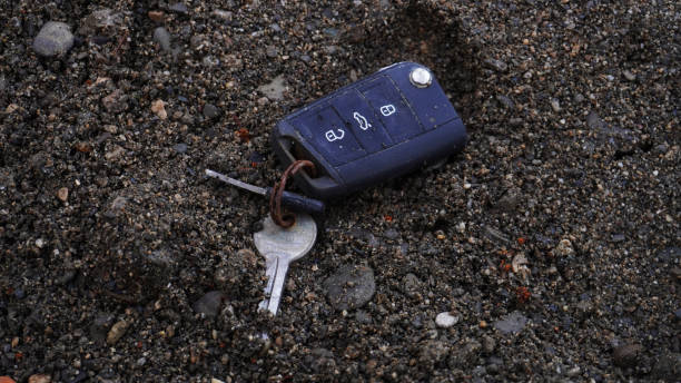 暗い砂の背景に、川のほとりに横たわる古い長い間紛失した車の鍵 - river knobs ストックフォトと画像