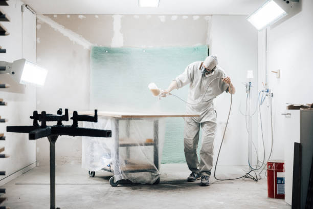 istock worker in protection wear varnishing wooden panel 1475557075