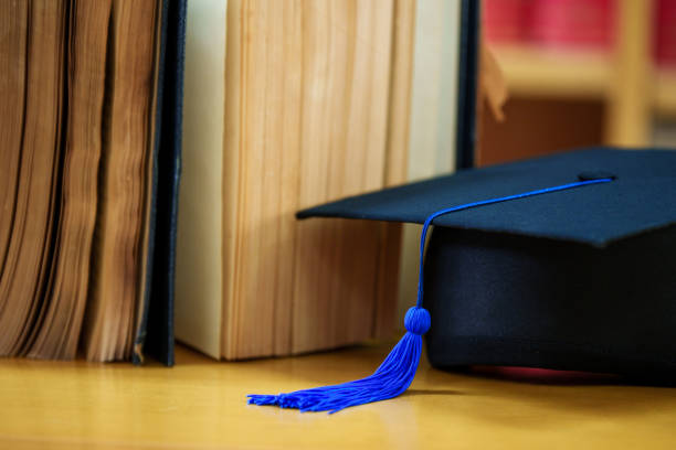 istock Black graduation hat place on a book in  classroom 1475557402