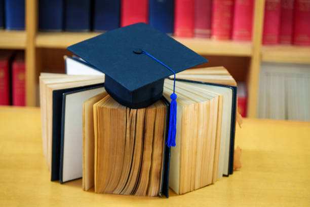 istock Black graduation hat place on a book in  classroom 1475557426