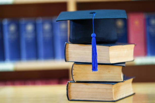 istock Black graduation hat place on a book in  classroom 1475557469