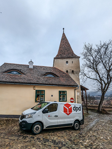 Sighișoara, Romania. March 16, 2023: DPD van makes a delivery through a window, on the cobbles of old town Sighișoara