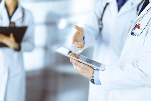 istock Group of doctors are checking medical names on the computer tablet, when a nurse with a clipboard is making some notes, while standing together in a hospital office 1475559113