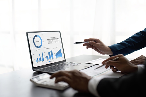 Two male accountants use calculator to calculate the company financial results with on data network connection of finance and and analytical research, income, tax and business growth.