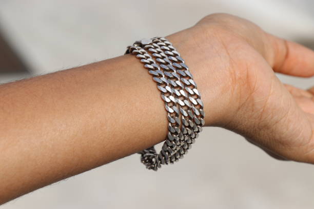 istock Pure silver chain that is worn as a bracelet on hand exposed to natural light. Silver chain with details of chain links 1475562876
