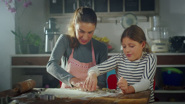 Portrait of Woman and Daughter in the Kitchen Baking Together. Mother Teaching her Little Girl How to Make Cookies. Female Child Helping her Mother with Cooking. Happy Childhood Memories