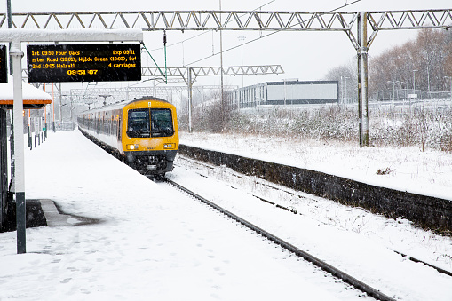 Duddeston, Birmingham,nUK - March 9, 2023.  A West Midlands Trains passenger service at a snow covered station platform with heavy snowfall causing travel disruption