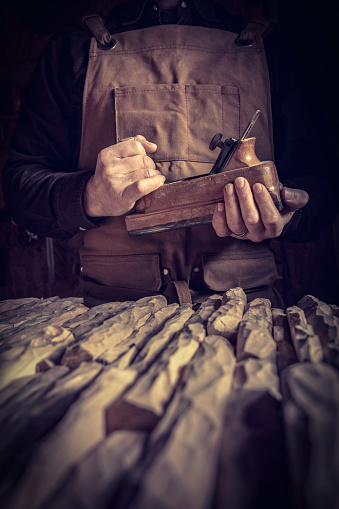 carpenter with leather apron holding a planer