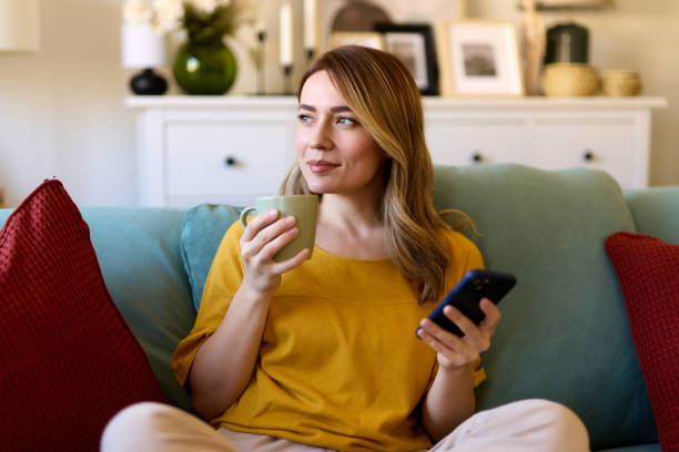 istock Woman using smartphone while drinking coffee at her home in the morning 1475572520