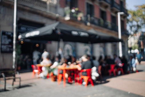 Blurred abstract background of outdoor cafe or restaurant. Outdoor cafe with tables and chairs. Street cafe in the afternoon in Valencia Spain . Customers sit at tables in a terrace area outside cafe.