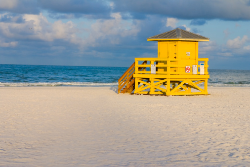 A yellow wooden lifeguard hut on an empty morning beach