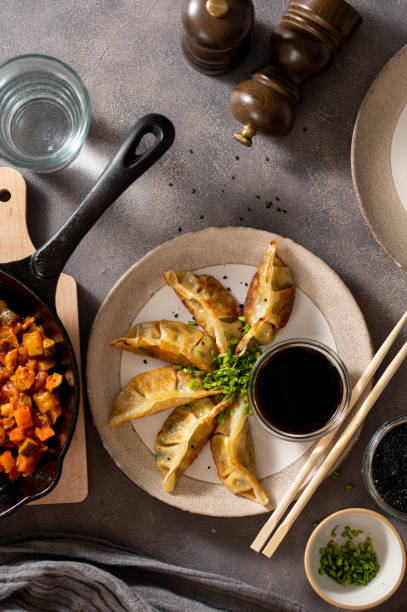 istock Fried dumplings gyoza with soy sauce and vegetable stuffing and chopsticks, top view. Dark background. 1475581029