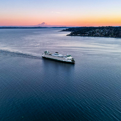 Aerial drone view of a Washington State Ferry in Kingston, WA Kitsap County. Mt Rainier and the city of Seattle in the background at sunset.
