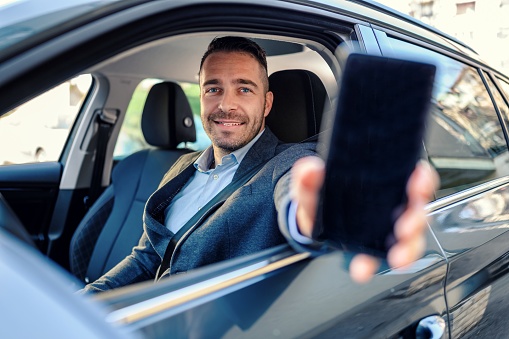 Man driving a car and showing the smart phone