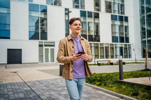 istock Young cheerful man using smartphone outdoor 1475590292