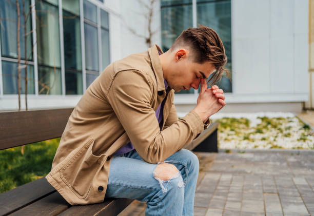 istock Young sad man sitting on the bench in the city 1475591220