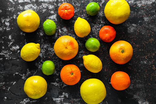 Healthy food, diet, nutrition, nature concept. Citrus fruits vitamin background. Orange, grapefruit, tangerine, lime, lemon with leaves on a grunge black table. Top view flat lay overhead