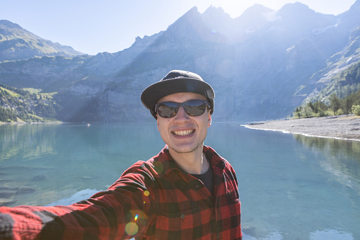 Happy hiker takes photo with the lake and mountains on background.
People travel outdoor activities in Summer