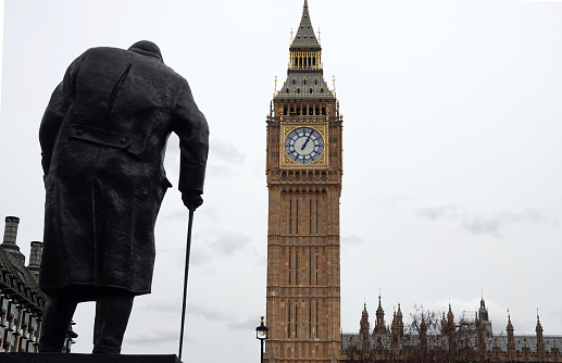 London, UK - March 15, 2023: A rear view of the statue of Sir Winston Churchill overlooking Big Ben and the Houses of Parliament in Westminster, London, England.