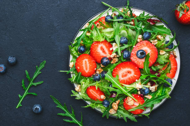 istock Strawberry and herbs healthy salad with arugula, blueberries and walnuts, black kitchen table, place for text. Fresh useful vegan dish for healthy eating 1475595414