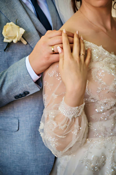 istock Elegant groom holding bride's hand, posing together outdoors on wedding day. 1475597647