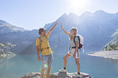 Two hikers celebrating success on top of rock with an high five