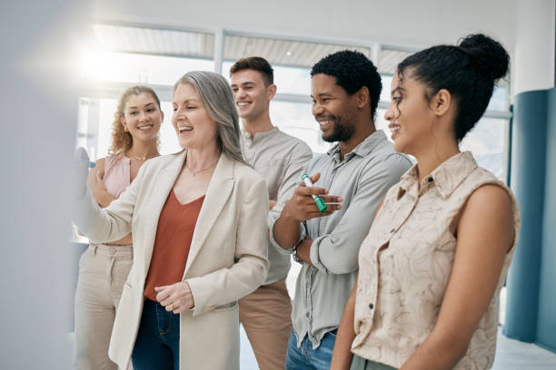 istock Meeting, teamwork and planning with a woman manager training or coaching her team in the office. Leadership, management and whiteboard with a senior female writing during a learning workshop 1475598099