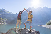 Two hikers celebrating success on top of rock with an high five