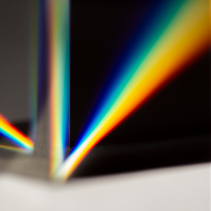 Triangular prism scattering solar beam splitting into a spectrum on white background