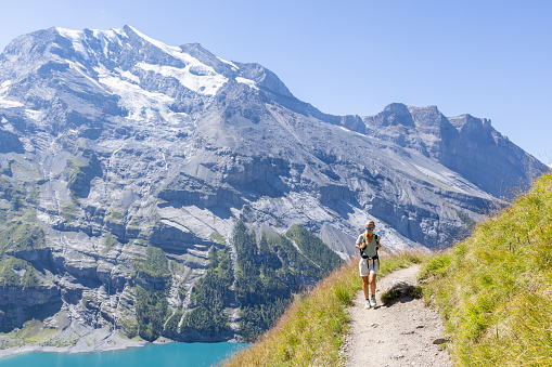 Berner Oberland canton, Switzerland\nShe walks on a trail along a beautiful blue lake in the center of Switzerland.