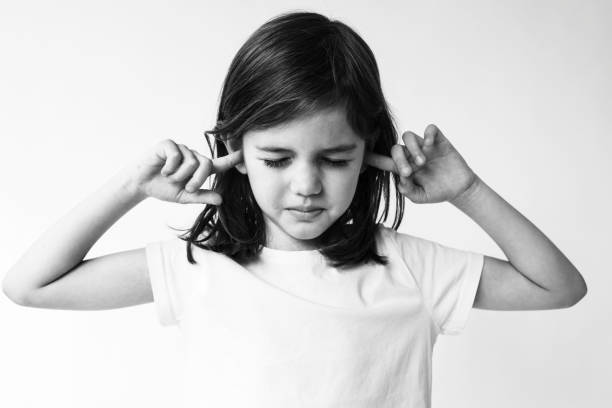 Little girl covering her ears with fingers isolated on white background.