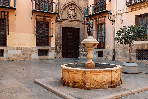 Ancient marble fountain with a statue in the ancient city center of Valencia Spain