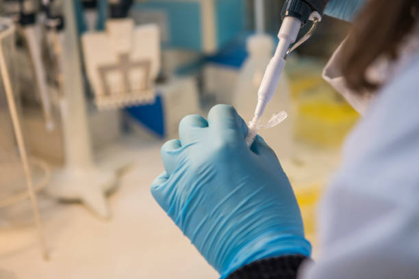 istock One hand holding  an eppendorf test tube with sample and a lab technician taking liquid with a micropipet in a laboratory. 1475620245