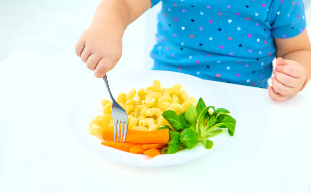 Child baby eats pasta with vegetables. Selective focus. Food.