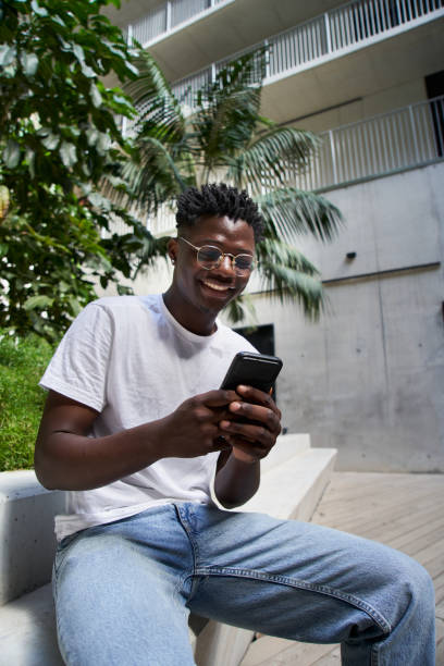 istock Vertical portrait smiling black boy using cell phone campus. Cheerful millennial people connecting. 1475623148