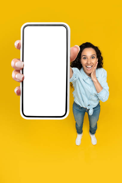 Excited woman showing blank mobile phone screen at studio