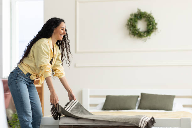 istock Pretty young smiling lady putting warm plaid on comfy sofa 1475624138